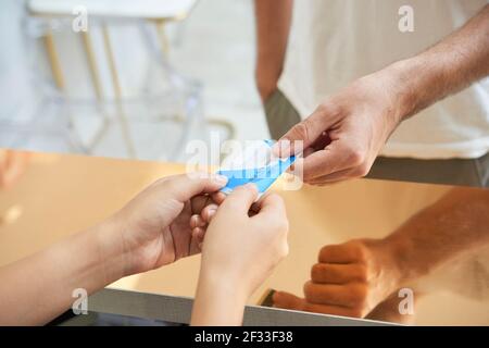 Immagine ravvicinata dell'uomo che dà carta di credito all'addetto alla reception pagare per la procedura in centro benessere o clinica Foto Stock