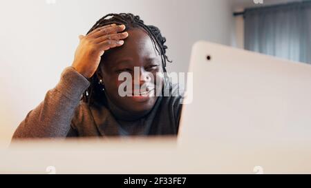 Uomo nero emozionale che mostra un regalo durante la videochiamata. Datazione online. Foto di alta qualità Foto Stock
