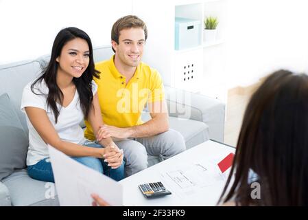 Giovane incontro di coppia interracial con agente immobiliare (o consulente finanziario) a casa Foto Stock