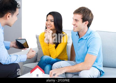 Giovane incontro di coppia interracial con agente immobiliare (o consulente finanziario) a casa Foto Stock