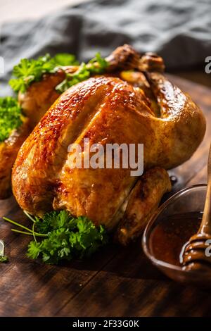 Pollo intero al forno con crosta di pelle smaltata con miele sulla parte superiore e prezzemolo sul lato. Foto Stock