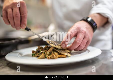 Chef che prepara il pesce sulle verdure e prepara il cibo per servire. Foto Stock
