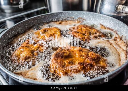 Schnitzel fritti in olio all'interno di una padella scura. Foto Stock