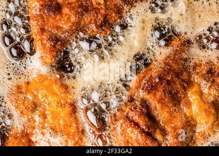 Dettaglio di schnitzel in pangrattato sfrigolante in olio di frittura. Foto Stock