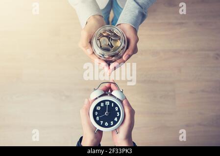 Mani che tengono il denaro scambiando con tempo, business e metafora finanziaria Foto Stock