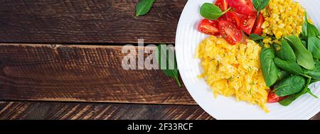 Colazione. Uova strapazzate con pomodori ciliegini, spinaci e mais. Vista dall'alto, banner, sopra