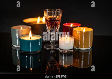 Candele profumate illuminate e riflettenti su una superficie nera lucida Foto Stock