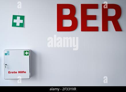 12 marzo 2021, Brandeburgo, Schönefeld: Un kit di pronto soccorso è appeso su un muro accanto alla scritta "BER" dell'aeroporto della capitale Berlino Brandenburg "Willy Brandt" (BER). Foto: Patrick Pleul/dpa-Zentralbild/ZB Foto Stock