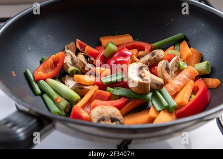 Una varietà di verdure colorate tagliate per friggere in un wok. Foto Stock