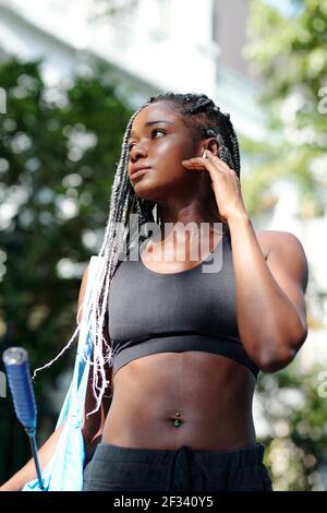 Ritratto di giovane donna nera piuttosto forte con capelli intrecciati camminare a casa dopo un allenamento all'aperto con badminton Foto Stock