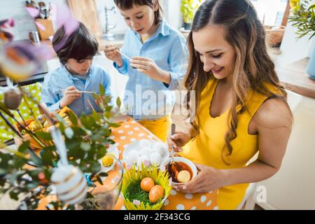 Primo piano di madre, figlio, e un amico colorazione uova per Pasqua Foto Stock