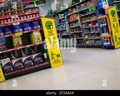 La segnaletica gialla in una filiale del supermercato britannico ASDA ricorda ai clienti di rimanere al sicuro coprendo il viso, mantenendo la distanza di sicurezza e facendo acquisti da soli. Foto Stock