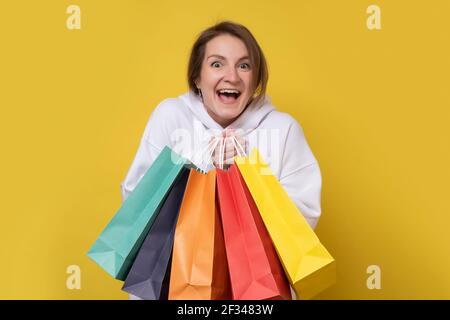 Shopping donna sorridente tenendo borse colorate isolato su sfondo giallo. Scatto in studio Foto Stock