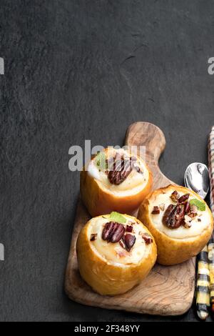 Mele al forno farcite con formaggio morbido e noci su nero sfondo di pietra Foto Stock