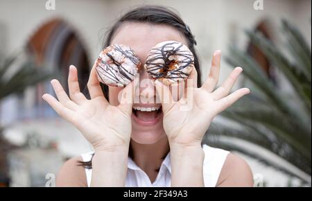 Ragazza divertente in posa con le ciambelle in estate all'aperto. Concetto di vacanza. Foto Stock