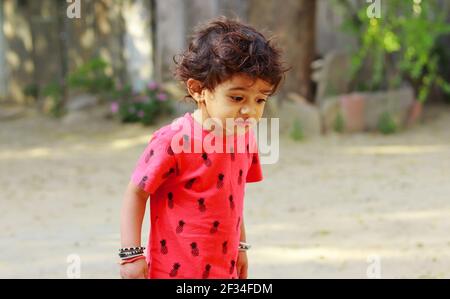 Un ragazzo piccolo di origine indiana che guarda la terra con stupore, india.Concept per le gioie dell'infanzia, i ricordi dell'infanzia, le espressioni del volto del bambino a. Foto Stock