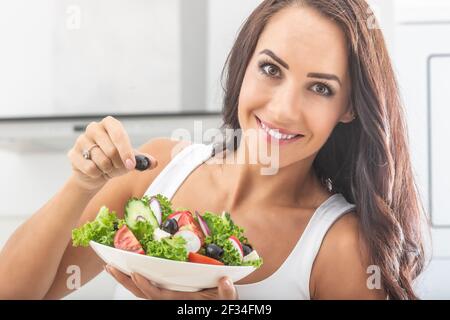 Brunette donna bella-Looking mangiare sana insalata colorata fitness con l'oliva in mano. Foto Stock