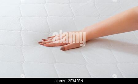 Donna che sceglie il nuovo materasso. Pressione manuale femminile materasso di prova per controllare la morbidezza. Scelta di comodi materassi per dormire in negozio. Controllo di qualità Foto Stock