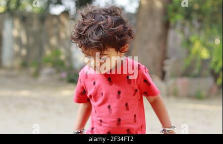 Un piccolo ragazzo di origine indiana che guarda la terra, india.Concept per le gioie dell'infanzia, i ricordi dell'infanzia, le espressioni del viso del bambino e il linguaggio del corpo , p. Foto Stock