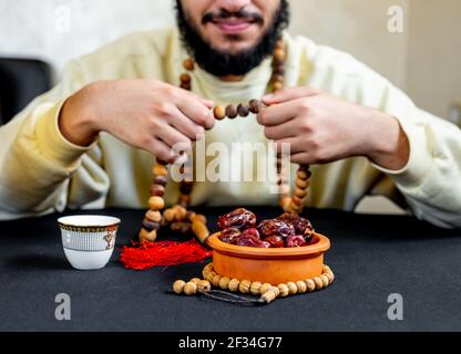 Uomo arabo musulmano che tiene il rosario con una certa data davanti di lui Foto Stock