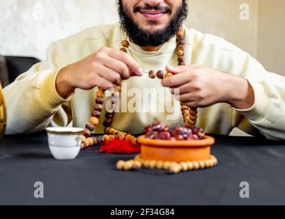 Uomo arabo musulmano che tiene il rosario con una certa data davanti di lui Foto Stock