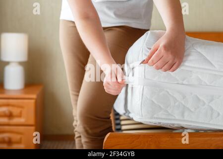 Donna ha indossato un nuovo materassino pulito sull'angolo del materasso ortopedico. Biancheria da letto a casa. Il foglio è indossato su un materasso morbido e pulito. Protezione da washe sporco Foto Stock