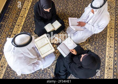 Vista dall'alto dei membri della famiglia musulmana che leggono insieme il quraan Foto Stock