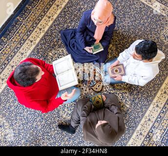 Vista dall'alto dei membri della famiglia musulmana che leggono insieme il quraan Foto Stock