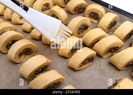 Applicare l'olio su pasta di lievito cruda appena preparata, con polpette di funghi all'interno, utilizzando una cazzuola da cucina in silicone. Foto Stock