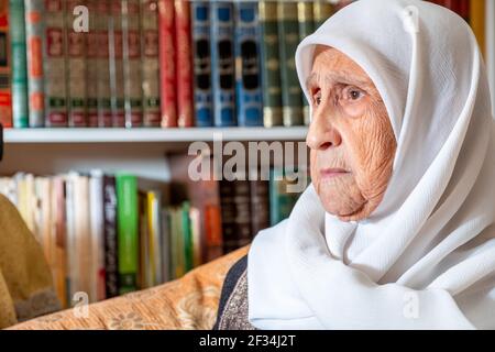 Vecchia donna musulmana araba seduta sul divano e sentendosi turbata Foto Stock
