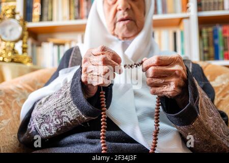 Uomo arabo musulmano che prega per dio usando il rosario Foto Stock