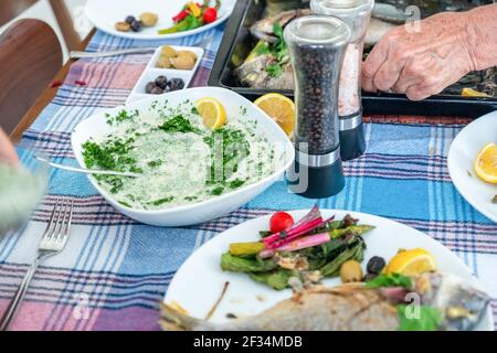 Famiglia che si riunisce per mangiare pesce insieme Foto Stock