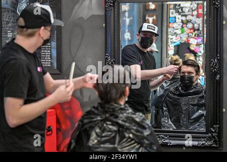 Barber Olly D'Urso taglia i capelli di David Saunders, 38, da Cardiff, a Sleep When You're Dead Barbers in Duke St Arcade, Cardiff, come David sta avendo il suo primo taglio di capelli dall'estate 2020. Parrucchieri e barbiere in Galles riapriranno da lunedì per la prima volta nel 2021, in quanto le restrizioni del coronavirus sono attenuate, segnando la prima revoca delle norme per i servizi di contatto ravvicinato da quando il Galles è entrato in blocco il 20 dicembre; Con le imprese come le unghie e saloni di bellezza si prevede di rimanere chiuso almeno fino ad aprile 12. Data immagine: Lunedì 15 marzo 2021. Foto Stock