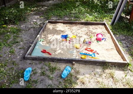 Sandbox all'aperto. Sandbox in legno per bambini con vari giocattoli per il gioco. Concetto estivo Foto Stock