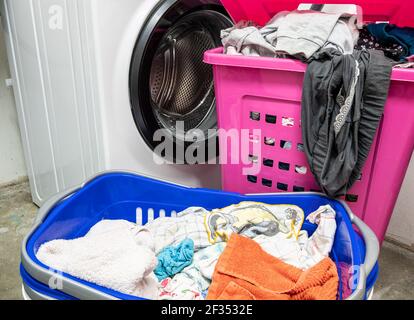 Cesto di bucato con lavanderia sporca e lavatrice a casa Foto Stock
