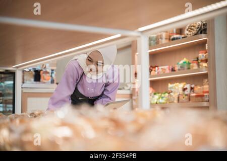 proprietario musulmano di affari che controlla il suo prodotto sul display dentro il negozio Foto Stock