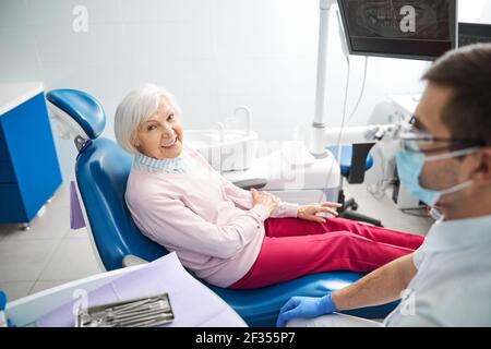 Paziente anziano che tiene il gomito vicino al medico Foto Stock