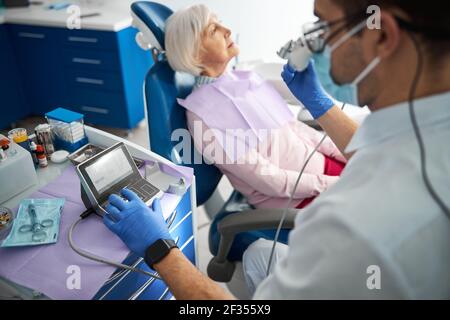 Il professionista del settore odontoiatrico utilizza un controller di perforazione elettrico Foto Stock