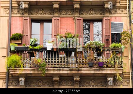 Pentole appesi al balcone con piante. Vecchio balcone con ornamenti alle pareti. Barcellona, Catalogna, Spagna. Foto Stock