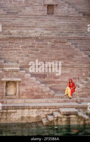 Donna in Sari in appoggio sui gradini a Toorji Ka Jhalara, la fase ben, Jodhpur, Rajasthan, India Foto Stock