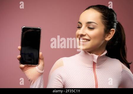 Giovane donna allegra che tiene il cellulare con display nero Foto Stock