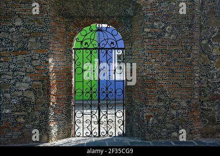 Muro di pietra lavorato a mano e cancello in ferro battuto ad arco della chiesa barocca Santa María Tonantzintla a Cholula, Puebla Messico. Foto Stock