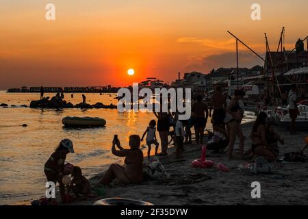 Ucraina, Porto di ferro - 22 agosto 2020: Tramonto sulla spiaggia di mare nella zona del resort con i vacanzieri in una serata estiva.