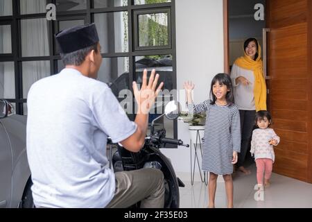 il padre asiatico musulmano che torna a casa dal lavoro è il benvenuto dalla sua famiglia a una porta d'ingresso Foto Stock