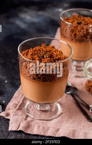 Mousse al cioccolato con brownie in vasi di vetro su un'ardesia scura, pietra o fondo di cemento. Delizioso dessert. Messa a fuoco selettiva. Foto Stock