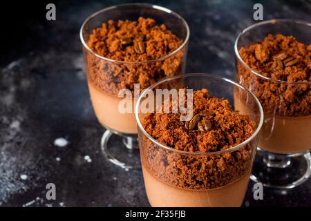 Mousse al cioccolato con brownie in vasi di vetro su un'ardesia scura, pietra o fondo di cemento. Delizioso dessert. Messa a fuoco selettiva. Foto Stock