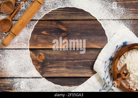 Farina sparsa sotto forma di cerchio, tondino e tovagliolo di lino bianco su un vecchio sfondo di legno. Posiziona per il testo. Sfondo per la cottura. Foto Stock