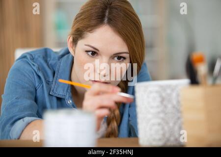 la donna tiene in mano una tazza per dipingere l'ornamento Foto Stock