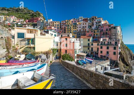 File di edifici dipinte in colori pastello in antichi villaggi delle cinque Terre, Liguria, Italia. Cielo blu chiaro. Foto Stock