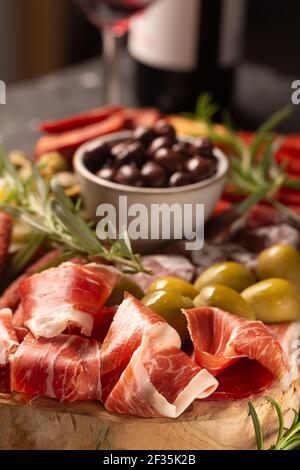 Salumi con jamon spagnolo, salsiccia di maiale con pepe, fuet, formaggio e bottiglia di vino rosso Foto Stock